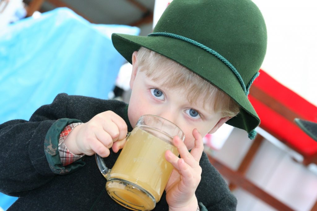 Kleiner Junge mit Trachtenhut trinkt Apfelsaft